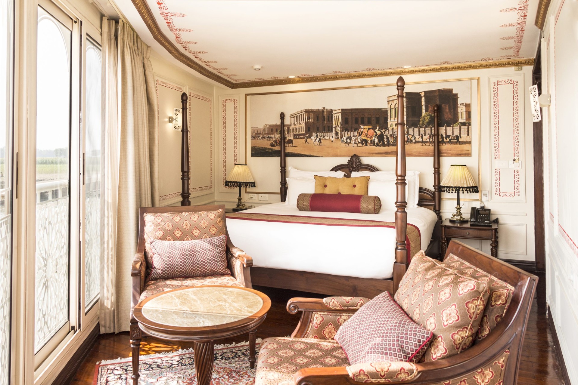 Heritage Suite aboard Ganges Voyager II with four-poster bed, colonial-era mural and river-view balcony