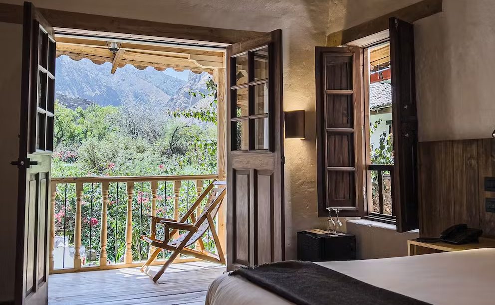Private wooden balcony at El Albergue Ollantaytambo with views of the surrounding Andean mountains