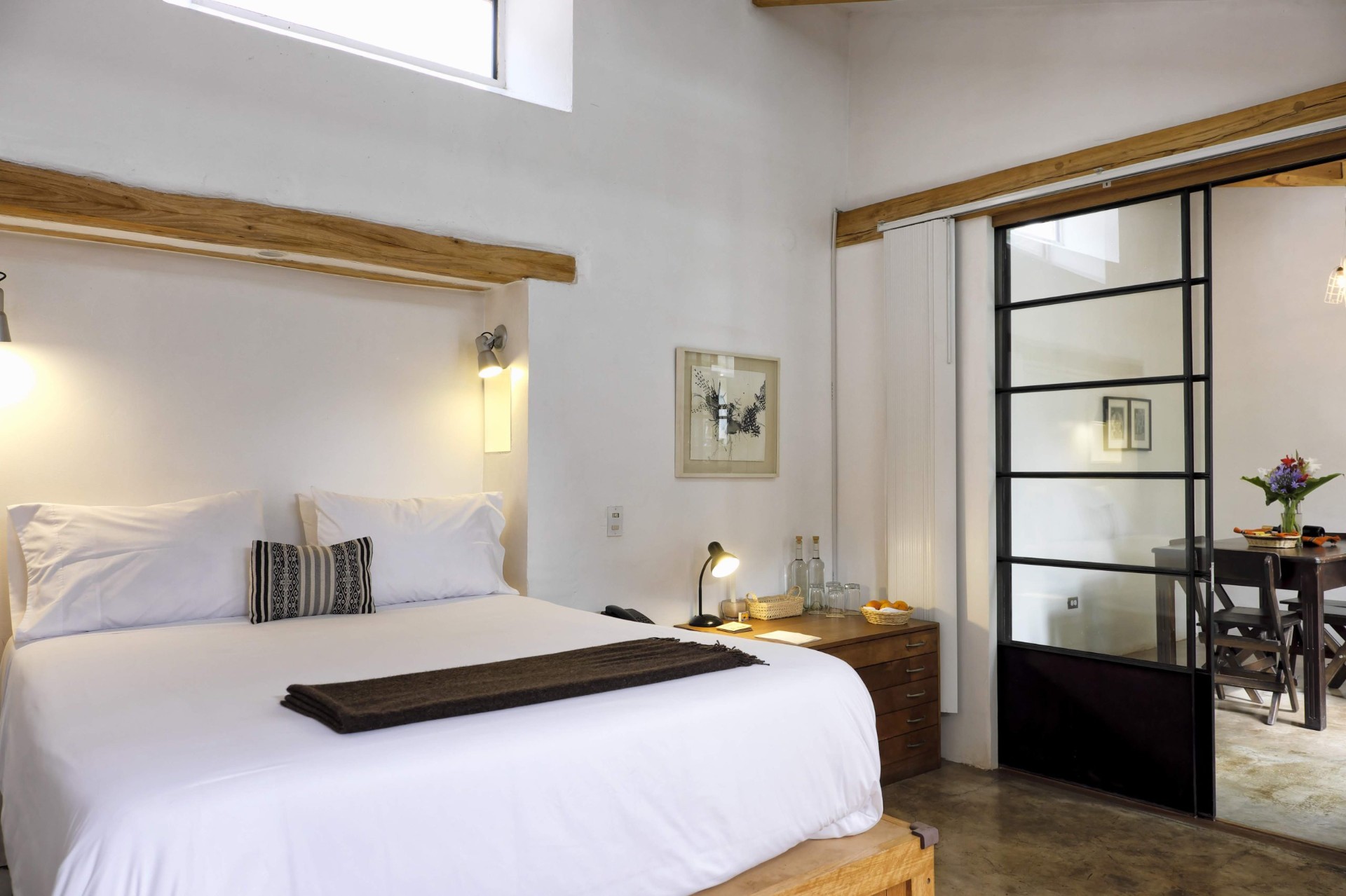Whitewashed guest room with wooden beams and minimalist Andean décor at El Albergue Ollantaytambo