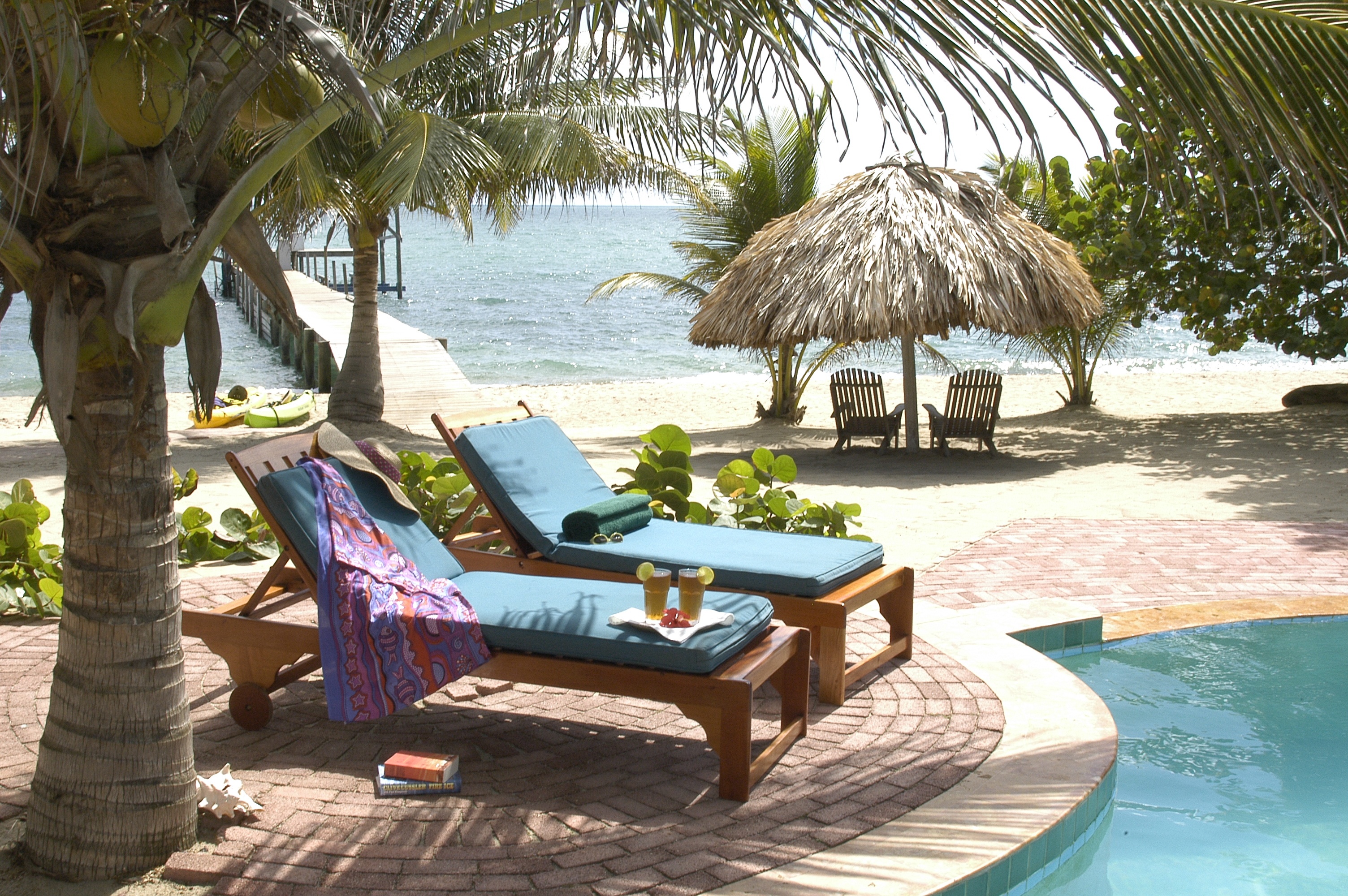 Beachside lounge chairs by the pool with palapa and ocean view