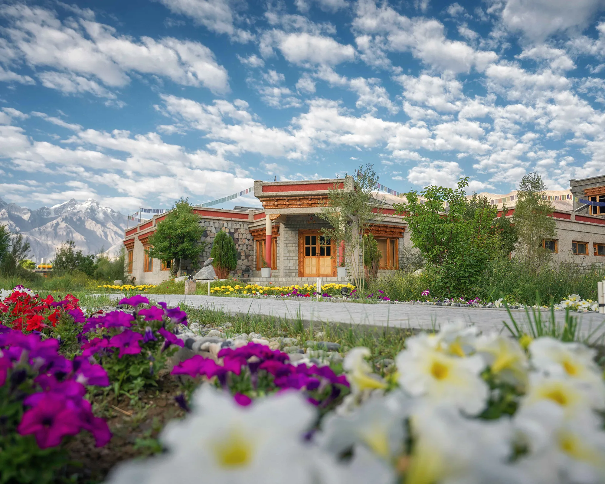 Lchang Nang Retreat exterior with flower gardens and Himalayan mountains