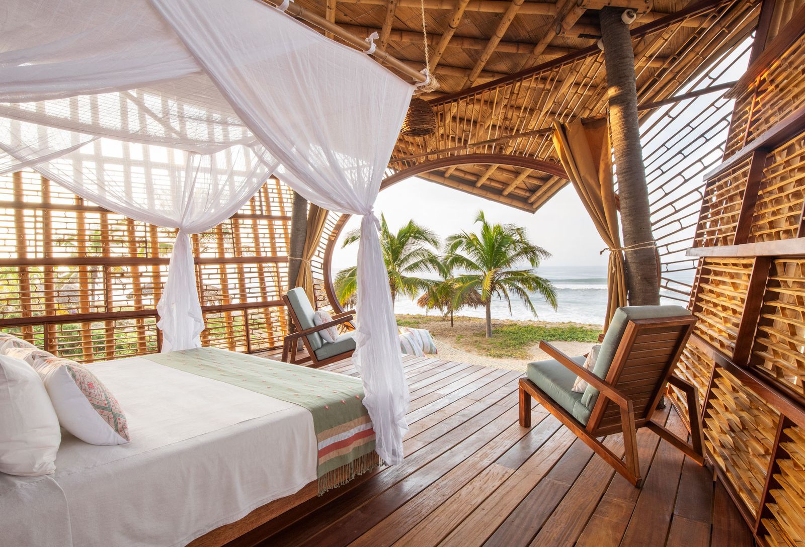 Open-air bamboo bedroom suite with canopy bed framing the Pacific at Playa Viva