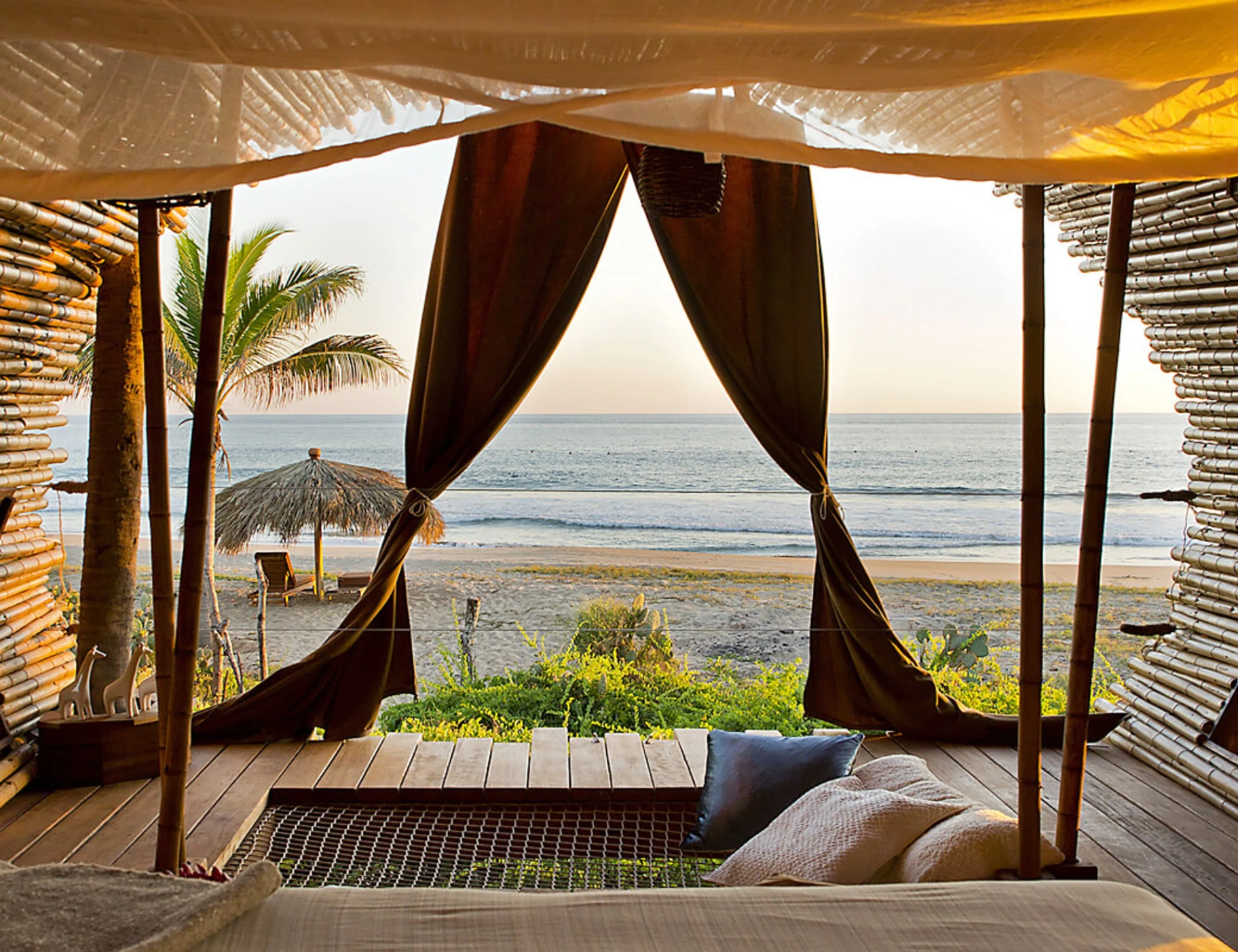 View from a Playa Viva bamboo villa through linen curtains to the Pacific surf at golden hour