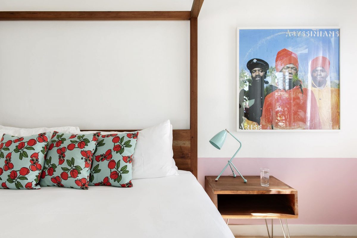 Skylark guest room with four-poster bed, pastel pink wall and Abyssinians reggae poster