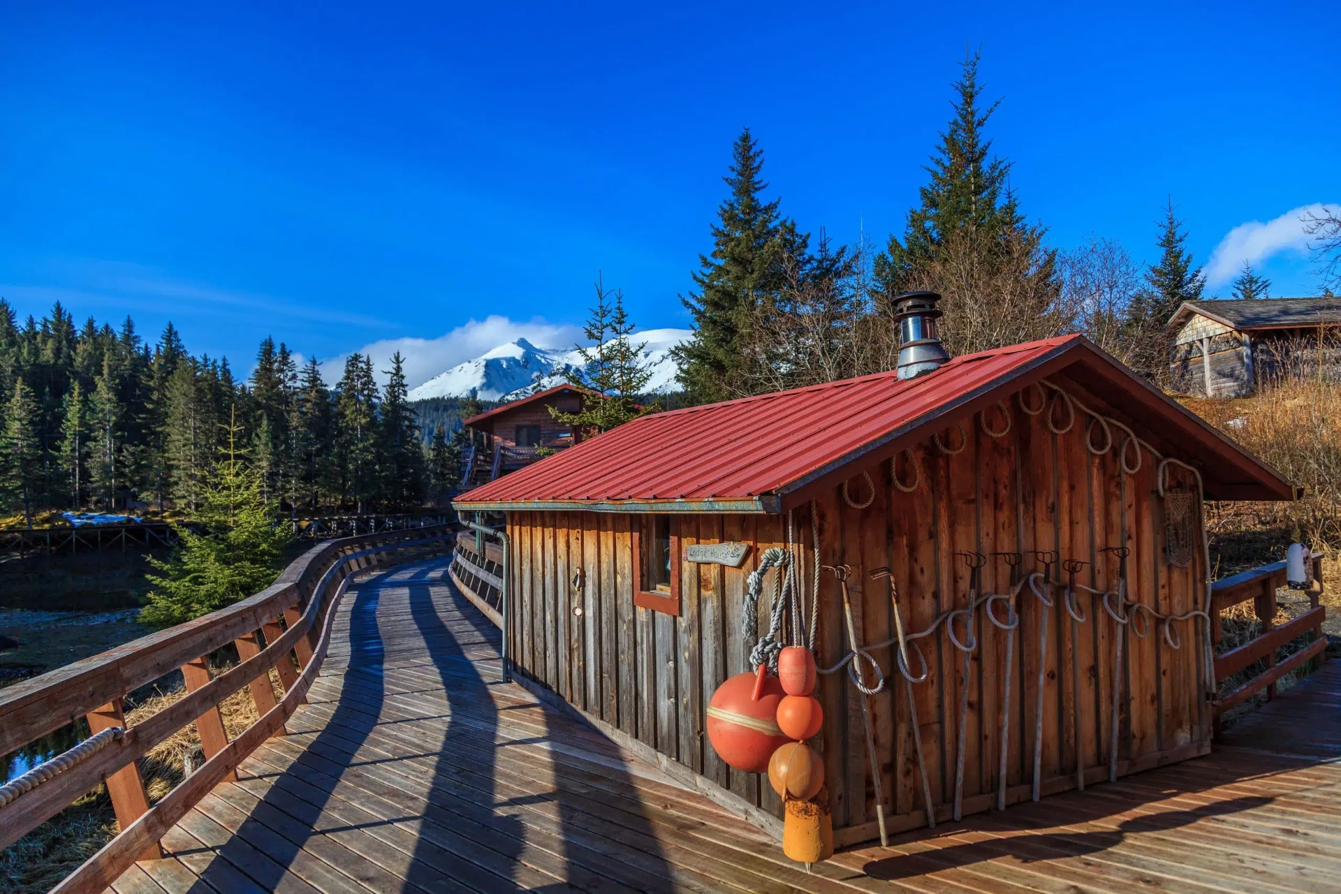 Lodge house and sauna along the boardwalk with snow-capped peaks beyond